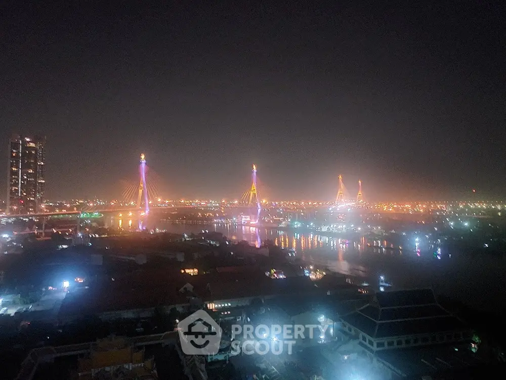 Stunning night view of illuminated cityscape with iconic bridge and river reflections.