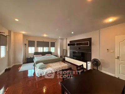 Spacious bedroom with elegant wooden flooring and modern entertainment unit