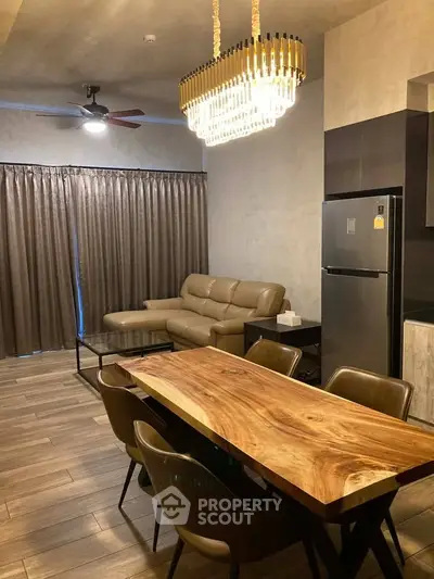 Modern living room with elegant chandelier and wooden dining table in stylish apartment.