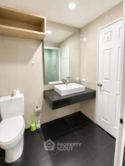 Modern bathroom with sleek design, featuring a wall-mounted sink and large mirror.