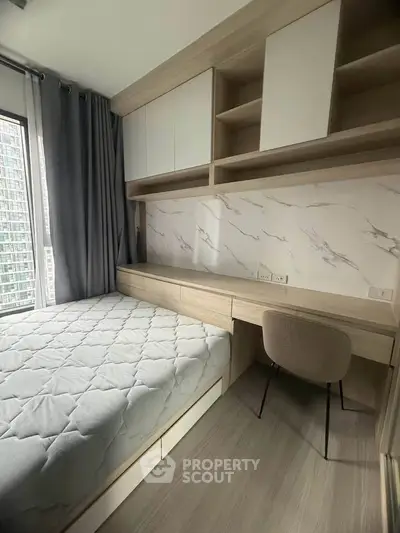 Modern bedroom with built-in storage and study area in a high-rise apartment.