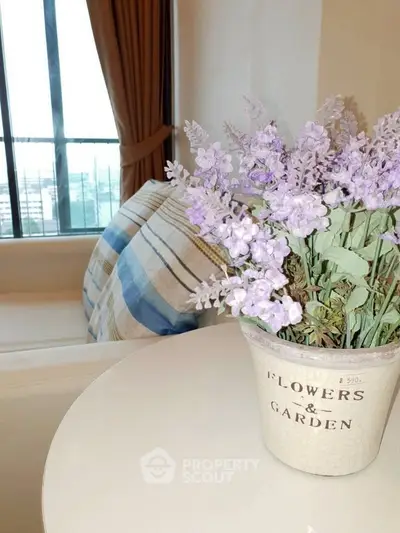 Charming interior with cozy seating and decorative lavender flowers in a stylish pot, perfect for relaxation.