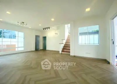 Spacious modern living room with elegant staircase and large windows