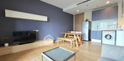 Modern living room with open kitchen, featuring sleek furniture and appliances in a stylish apartment.