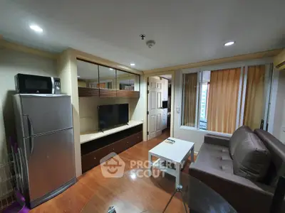 Modern living room with sleek furniture and appliances, featuring a cozy sofa and large fridge.