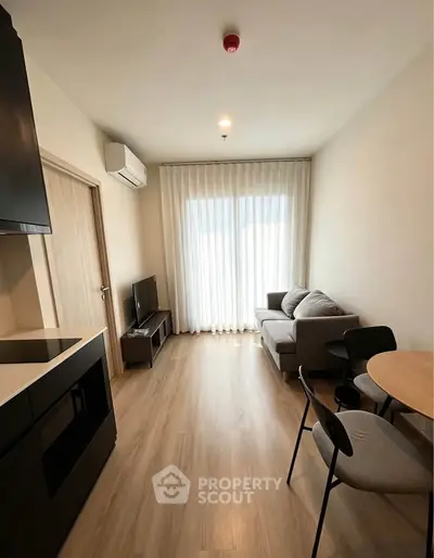 Modern living room with cozy sofa, TV, and dining area in a bright apartment.