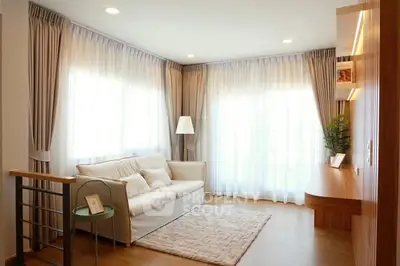 Elegant living room with natural light, cozy sofa, and stylish decor.