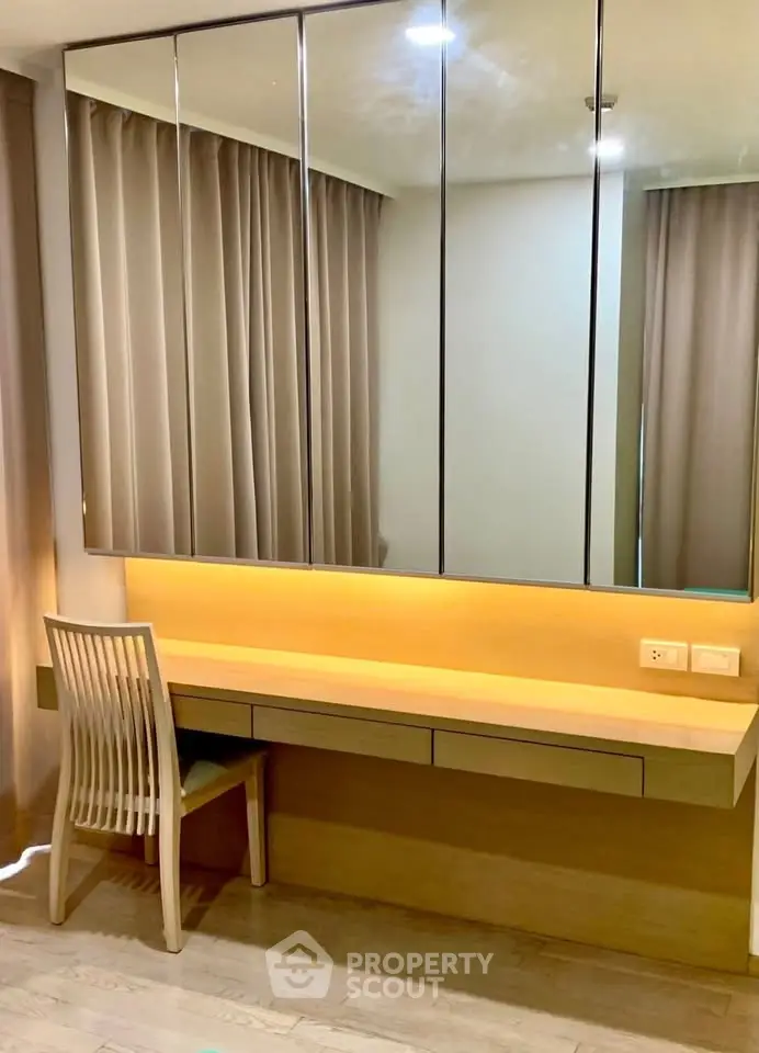 Modern study area with sleek wooden desk and mirrored cabinets in a stylish apartment.