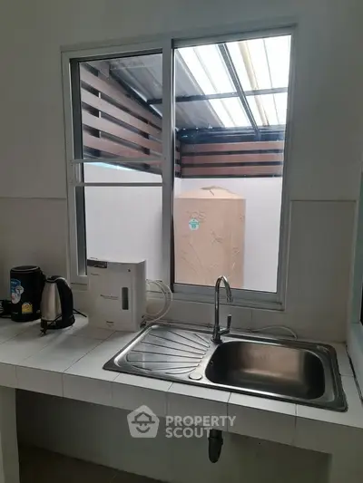Modern kitchen with sleek sink and appliances, featuring a window view to an outdoor area.