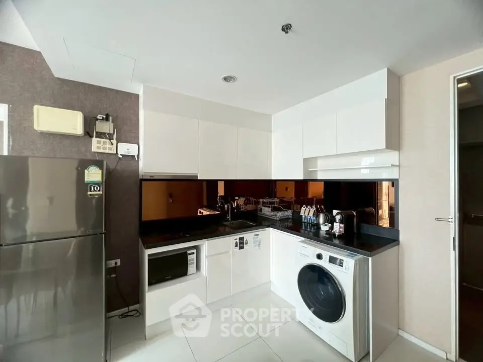 Modern kitchen with sleek appliances and glossy white cabinets in a contemporary apartment.