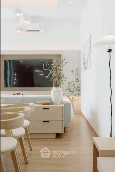 Modern living room with stylish furniture and large TV, featuring elegant decor and natural lighting.