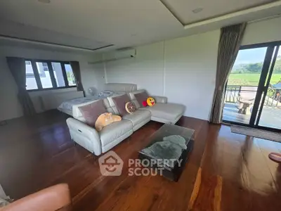 Spacious living room with wooden floors and large windows offering scenic views.
