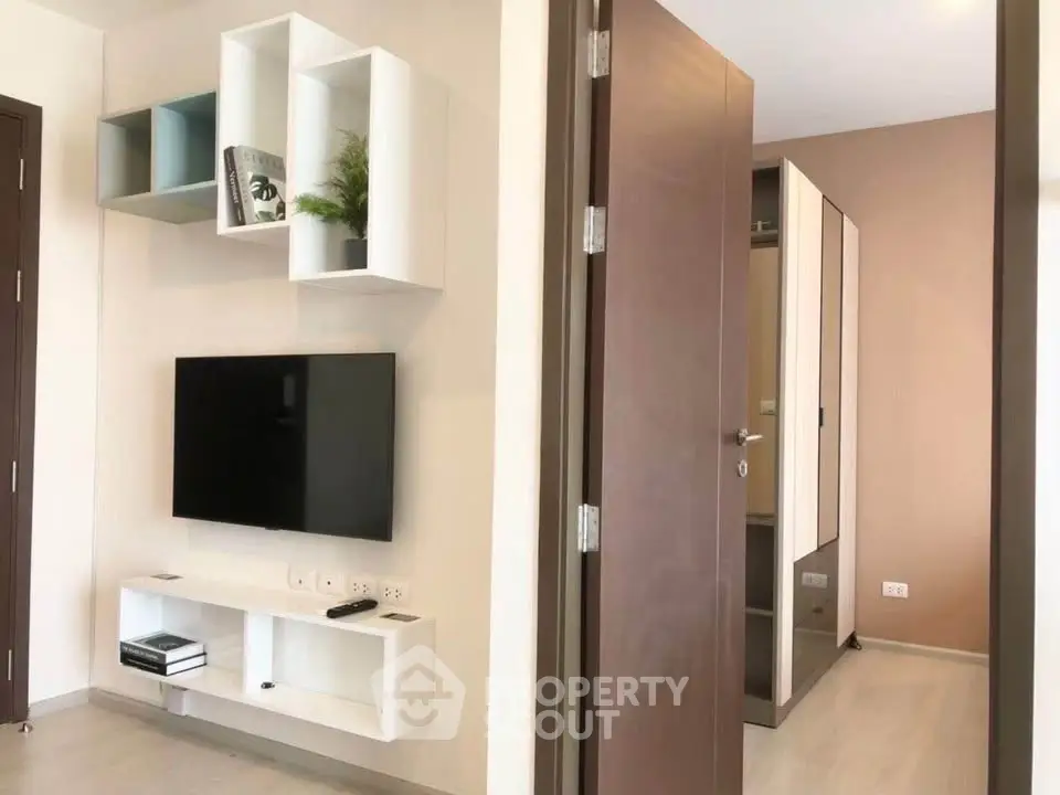 Modern living room with wall-mounted TV and stylish shelving in a contemporary apartment.