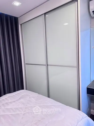 Modern bedroom with sleek sliding closet doors and cozy bedding.
