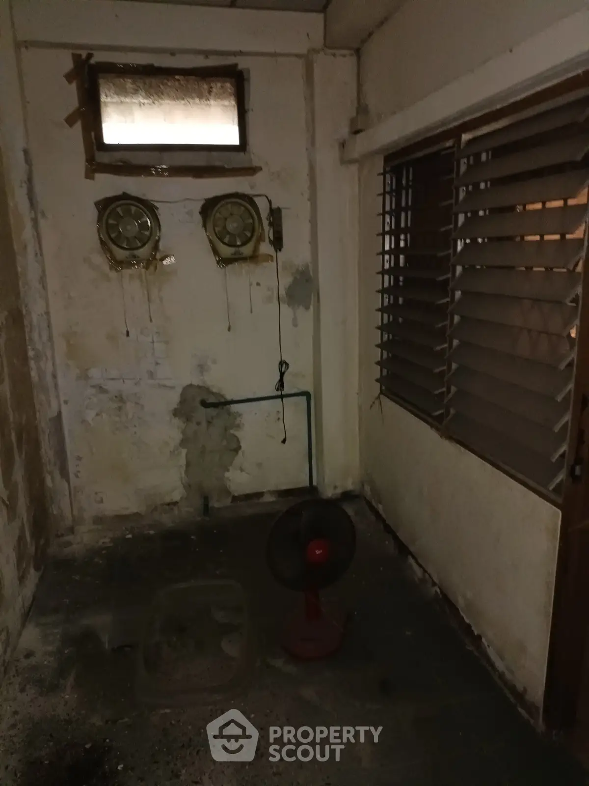 Dimly lit storage room with fan and ventilation system, potential for renovation.