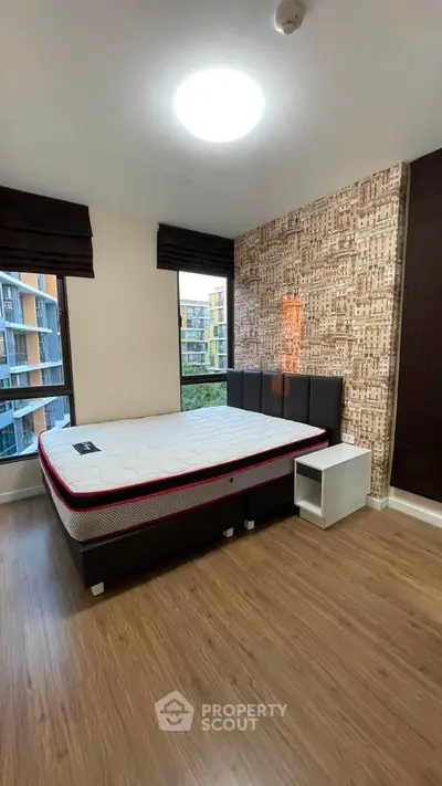 Modern bedroom with stylish wallpaper and large windows in a contemporary apartment.