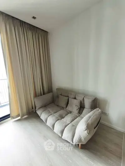 Cozy living room with plush sofa and floor-to-ceiling curtains, perfect for relaxation.