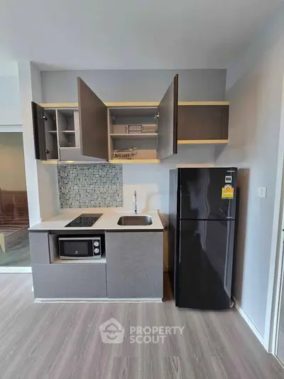 Modern compact kitchen with sleek cabinetry and appliances in a stylish apartment.
