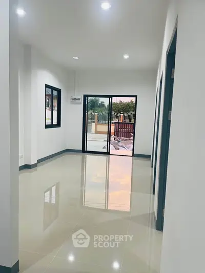 Spacious modern interior with glossy tiled floors and large windows, perfect for natural light.