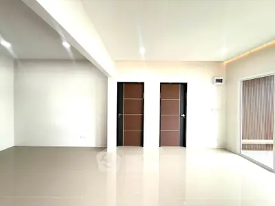 Spacious modern living room with sleek tile flooring and elegant wooden doors.