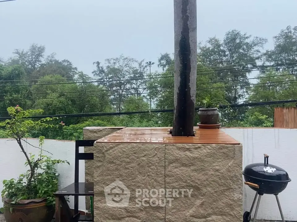 Charming outdoor BBQ area with lush greenery and rustic stone design, perfect for entertaining.