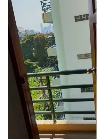 Charming balcony view with lush greenery and cityscape in the distance.