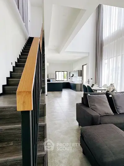 Modern open-plan living room with high ceilings and stylish staircase