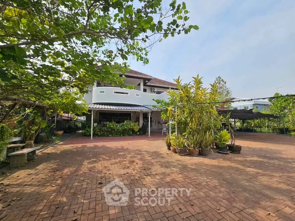 Spacious suburban home with lush garden and expansive brick patio, perfect for outdoor living.