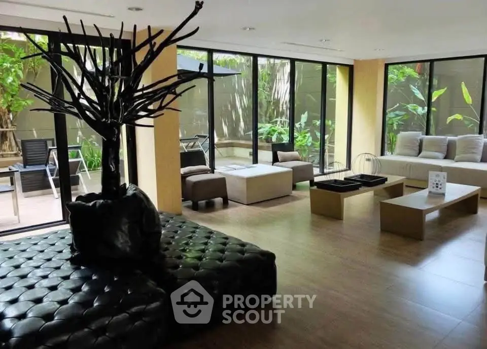 Spacious modern living room with large windows and stylish furniture, offering a serene garden view.