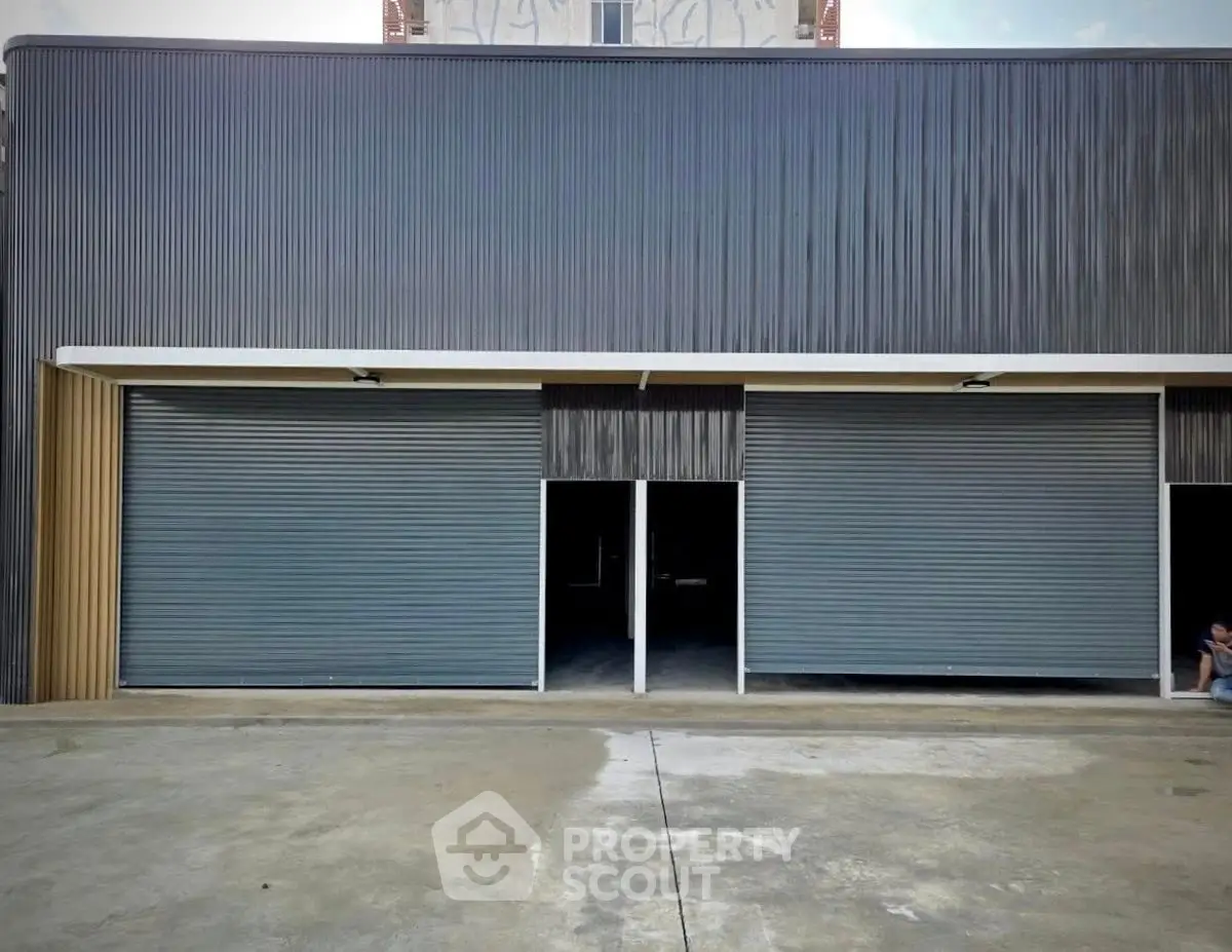 Modern industrial warehouse with large roller doors and spacious concrete forecourt.