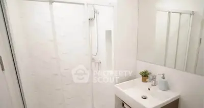 Modern bathroom with sleek shower and stylish vanity in bright white decor.