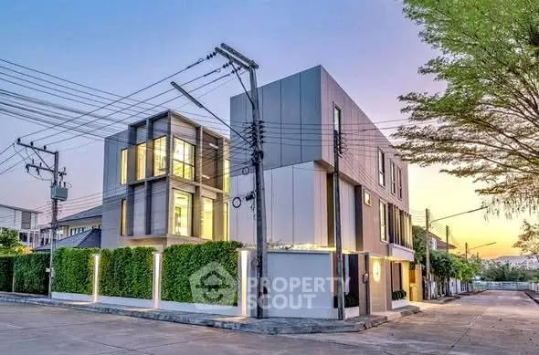 Modern three-story building with sleek design and lush greenery in a serene neighborhood.
