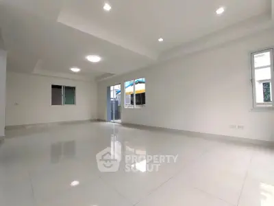Spacious modern living room with large windows and sleek tile flooring.
