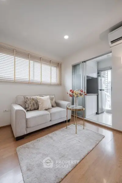 Modern living room with cozy sofa and open kitchen layout, featuring sleek appliances and stylish decor.