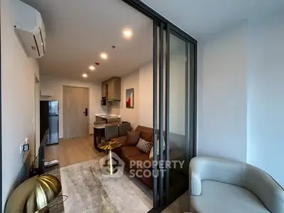 Modern living room with sleek furniture and open kitchen layout in a stylish apartment.