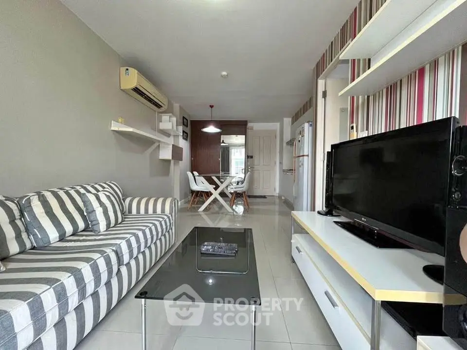 Modern living room with striped sofa, glass coffee table, and wall-mounted air conditioner in stylish apartment.
