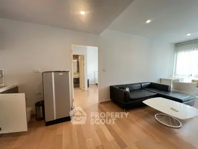 Spacious modern living room with sleek black sofa and wooden flooring, perfect for contemporary living.