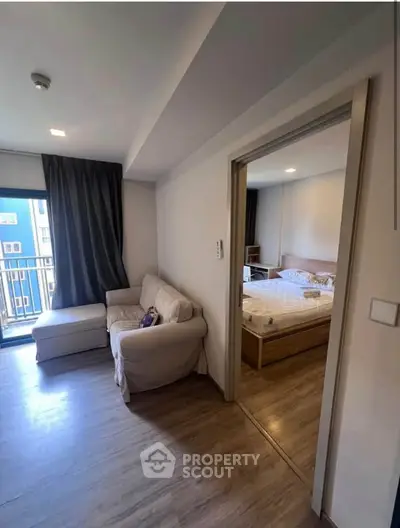 Modern apartment interior with cozy living room and bedroom, featuring wooden flooring and natural light.