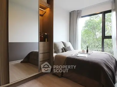 Cozy bedroom with large window and mirrored wardrobe in modern apartment