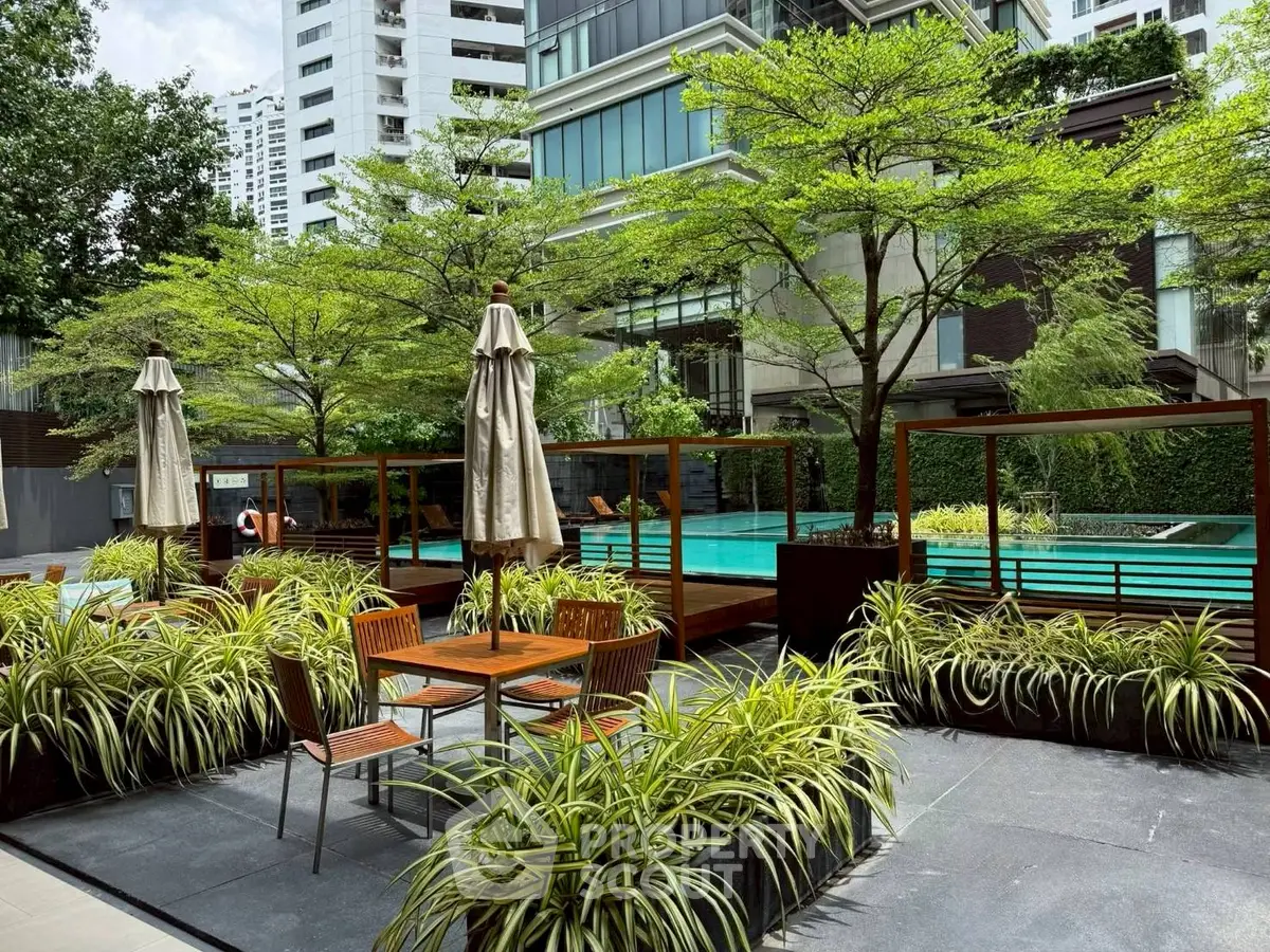 Luxurious outdoor pool area with lush greenery and modern seating in a high-rise residential complex.