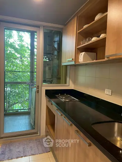 Modern kitchen with sleek cabinets and balcony view, featuring a compact open layout and natural light.