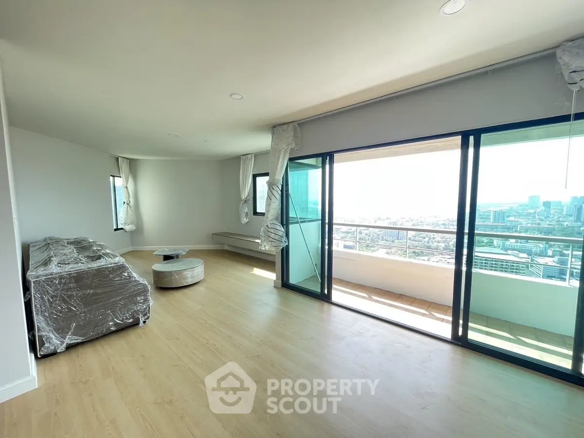 Spacious living room with large balcony and city view, perfect for urban living.