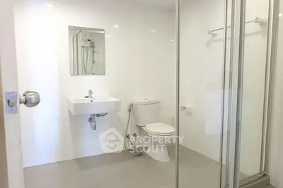Modern bathroom with glass shower and sleek fixtures in minimalist design.