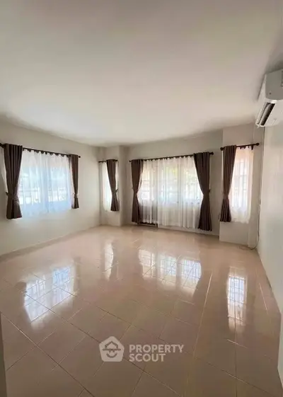 Spacious empty living room with large windows and tiled floor