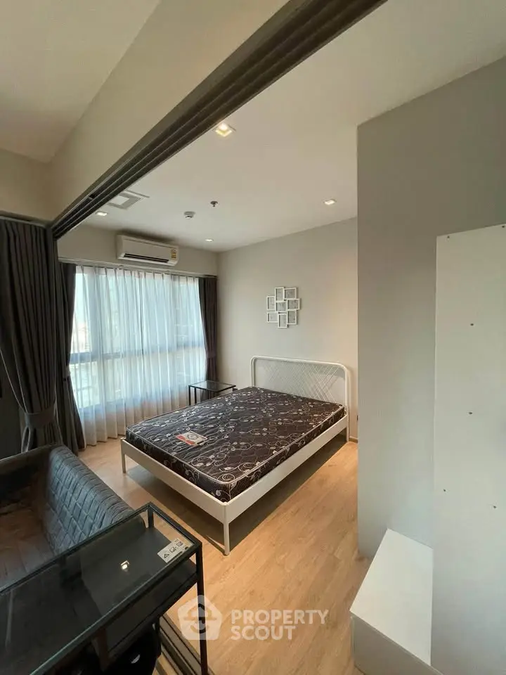 Modern bedroom with large window, stylish decor, and cozy atmosphere in a contemporary apartment.