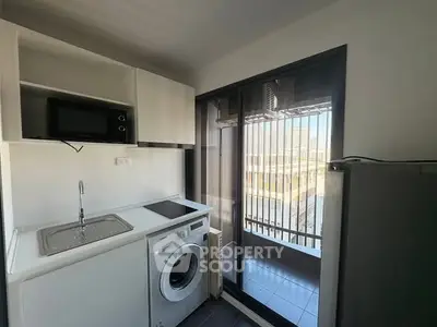 Compact kitchen with modern appliances and balcony view in urban apartment