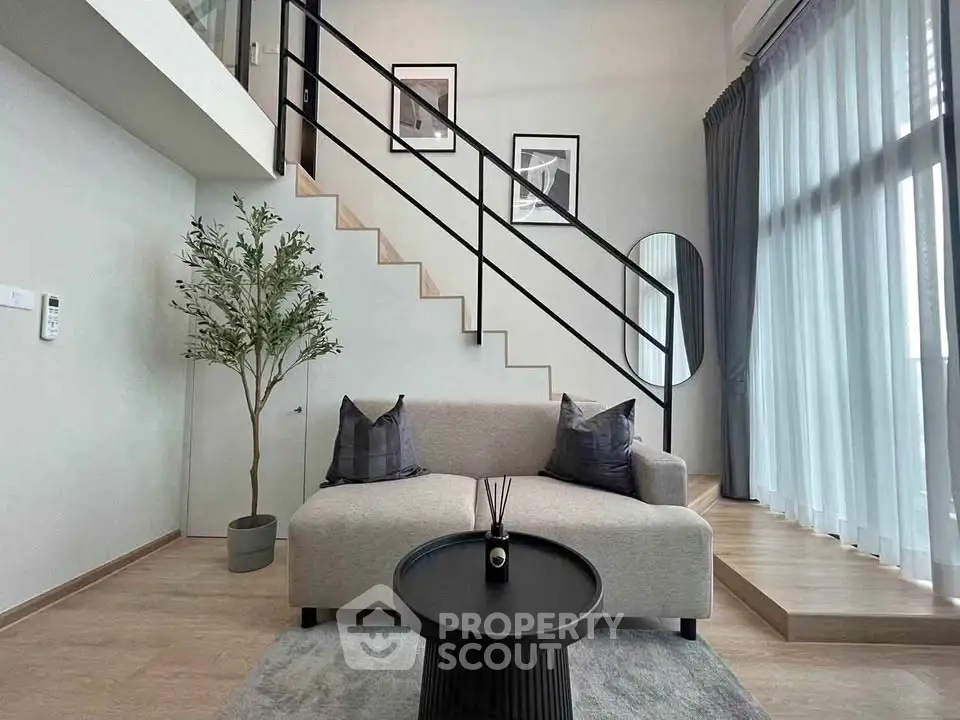 Modern living room with stylish staircase and cozy seating area in a bright, airy space.