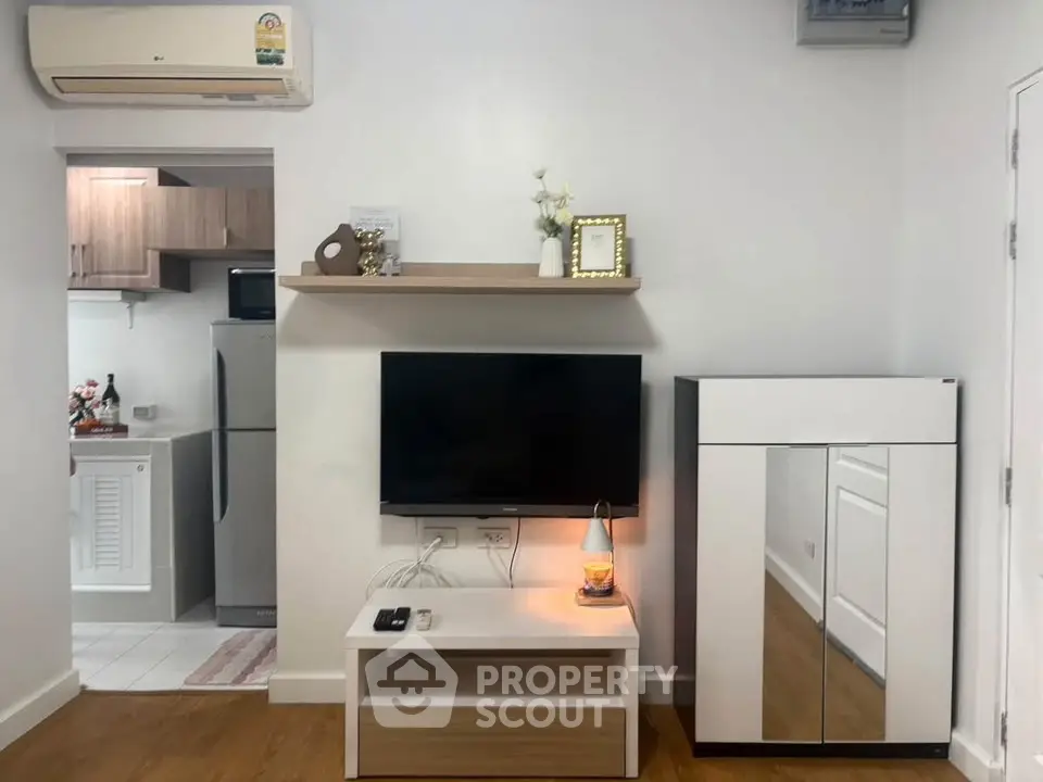 Modern living room with wall-mounted TV and sleek kitchen view