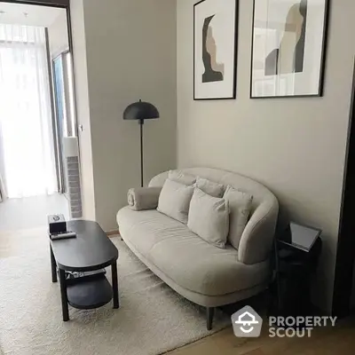 Chic modern living room with plush sofa, elegant art, and minimalist decor, bathed in natural light from the adjacent balcony.