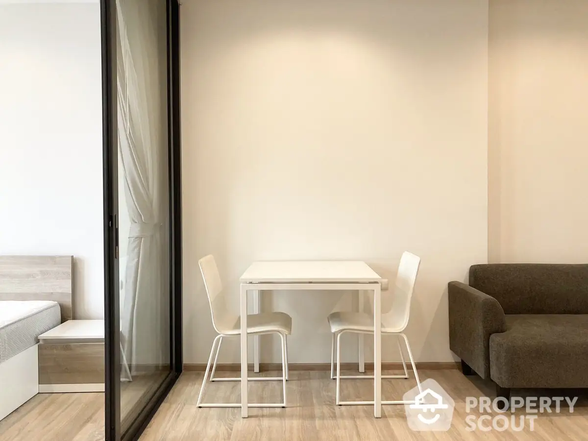 Modern minimalist living room with clean lines, featuring a sleek white dining table, comfortable seating, and warm wooden flooring, perfect for urban living.